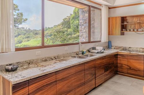 eine Küche mit einem Waschbecken und einem großen Fenster in der Unterkunft Cloud Forest House Monteverdes in Monteverde Costa Rica