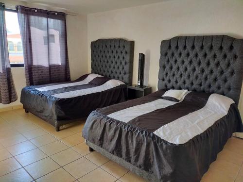 a bedroom with two beds and a tv in it at Ubicacion Privilegiadadepartamento En El Centro in Almoloya de Juárez