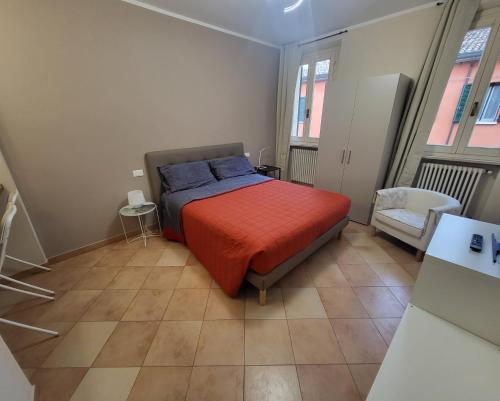 een slaapkamer met een bed en een stoel en 2 ramen bij La Rosa Cesena in Cesena