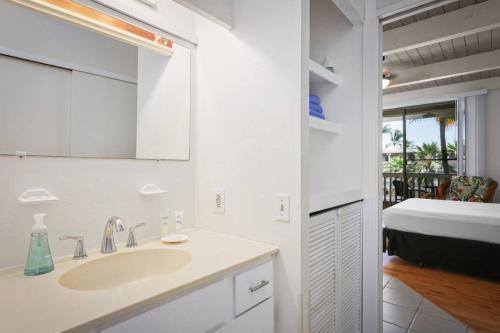 a bathroom with a sink and a mirror and a bed at Kona Bali Kai Unit 362 Partial Ocean View Studio in Kailua-Kona