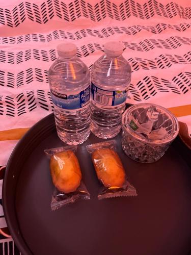 - une table avec 2 bouteilles d'eau et quelques aliments dans l'établissement Appartement La parisienne, à Fresnes
