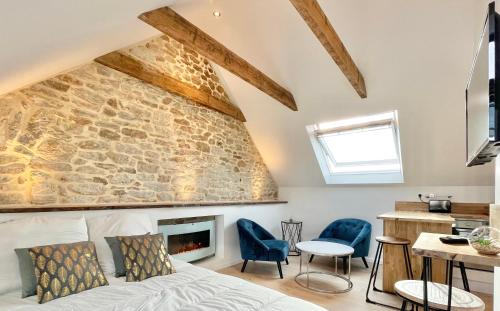 - une chambre avec un mur en pierre, un lit et des chaises dans l'établissement LE CALLOCH 3D - Standing - Calme - Wifi - Smart TV, à Quimper