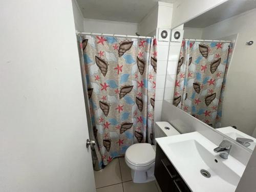 La salle de bains est pourvue de toilettes et d'un rideau de douche. dans l'établissement Cozy Apartment Near Airport, Secure, and Versatile, à La Serena