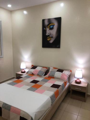 a bedroom with a bed with two night stands with lamps at CHEZ CODOU Fann Hock in Dakar