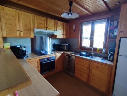 een keuken met houten kasten, een wastafel en een fornuis bij Le Mont Céleste in Nonceveux