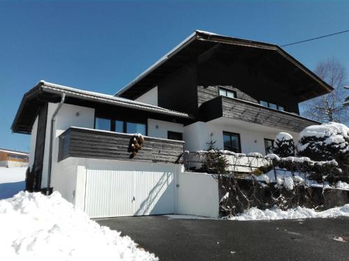 una casa con una cerca blanca en la nieve en Appartement Seebacher, en Hochfilzen