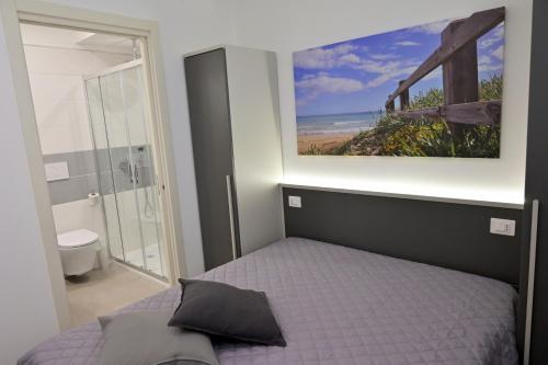 una camera con letto e una foto dell'oceano di Altamarea Beach Experience Villetta SE a Marina di Pescoluse