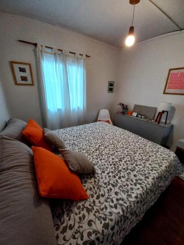 um quarto com uma cama grande e almofadas laranja em Habitación con Baño Privado - Frigo bar y sector para desayunar - Sin cocina em Ushuaia