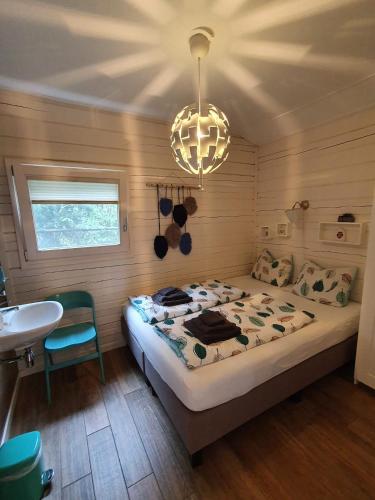 a bedroom with a bed and a sink and a chandelier at Vakantiewoning Hegga in Hegelsom
