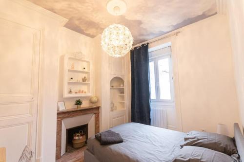 - une chambre avec un lit, une cheminée et un lustre dans l'établissement Immeuble L'aristocrate - Le Nuage - Bd Carnot, à Angers