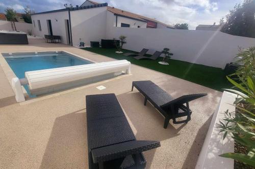 une arrière-cour avec une piscine et deux bancs noirs dans l'établissement L'escale de Courçon, à Courçon