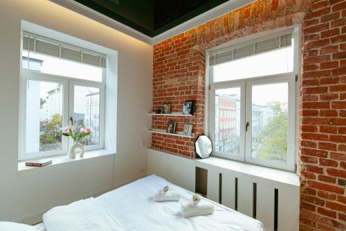 a bedroom with two windows and a brick wall at Wspólna 54a - Bezpłatny parking - Apartament dla 6 osób - 450 metrów od Dworca Centralnego i Złotych Tarasów - Better Rental in Warsaw