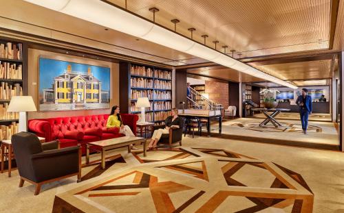 a library with two people sitting on a red couch at The Charles Hotel in Harvard Square in Cambridge