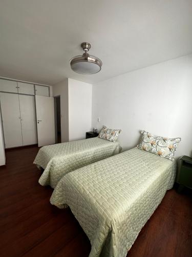 2 Betten in einem Zimmer mit weißen Wänden und Holzböden in der Unterkunft Refugio Urbano in Neuquén