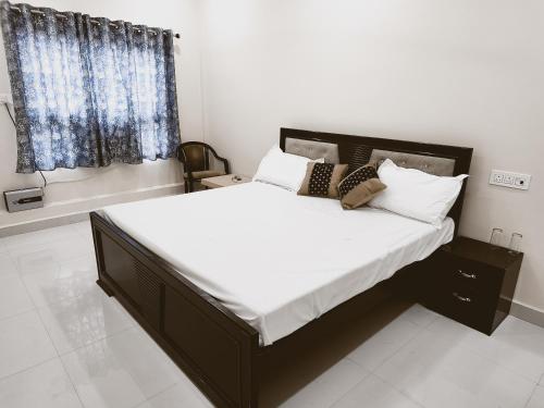een slaapkamer met een groot bed met witte lakens en kussens bij Saryu Lodge near Ram Janam Bhumi in Ayodhya