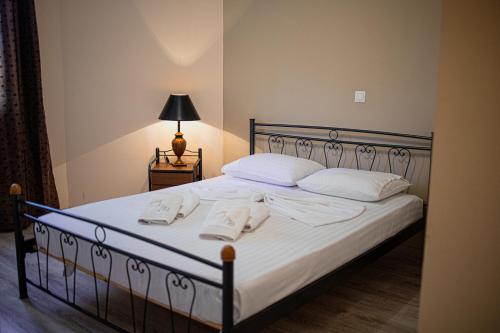 a bedroom with a bed with white pillows and a lamp at Villa Eridos in Káto Lekhónia