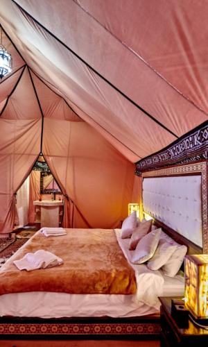 a bedroom with a bed in a tent at Luxury Sahara Camp in Merzouga