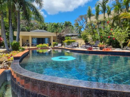 a swimming pool in front of a house at Black Rock Villas in Rarotonga