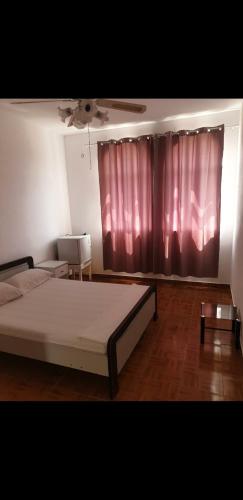 a bedroom with a bed and a red curtain at Residencial/ Pensão Natur in Tarrafal