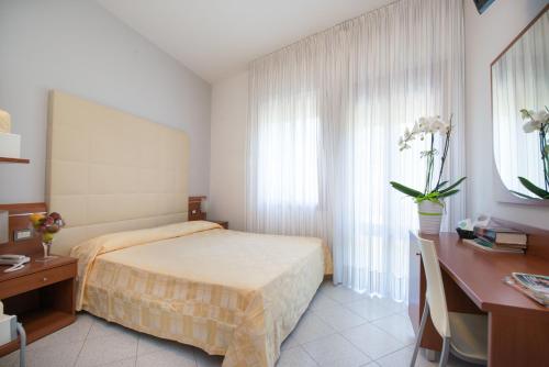 a bedroom with a bed and a desk and a window at Albergo Arcobaleno in Sottomarina