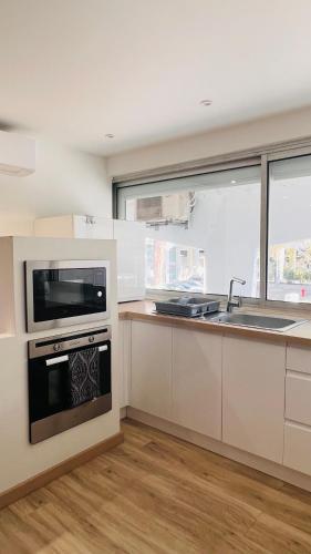 une cuisine blanche avec un évier et une cuisinière dans l'établissement Les Appartements De Lina - Appartement Cosy - Self Check-In -, à La Grande Motte