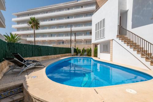 a swimming pool in front of a building at Apartamentos Marivent in Portocolom