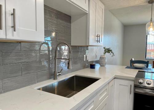 uma cozinha com um lavatório de aço inoxidável e armários brancos em Pasado Del Rio, Downtown getaway em Lake Havasu City