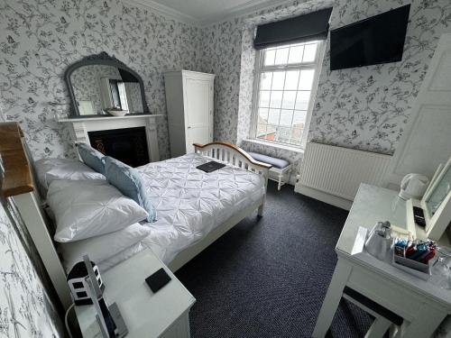 ein Schlafzimmer mit einem Bett, einem Spiegel und einem TV in der Unterkunft Caer Menai in Caernarfon