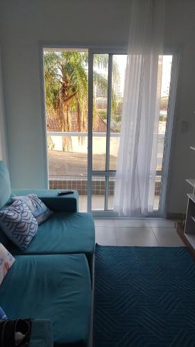 ein Wohnzimmer mit einem Sofa und einem großen Fenster in der Unterkunft Apartamento 2 quartos próximo da praia in Praia Grande