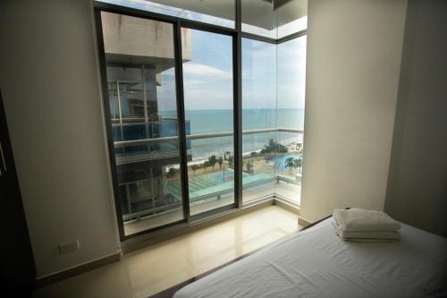 ein Schlafzimmer mit großem Fenster mit Blick auf das Meer in der Unterkunft DEPARTAMENTO DE LUJO FRENTE AL MAR, WIFFI PISO 8 in Tonsupa
