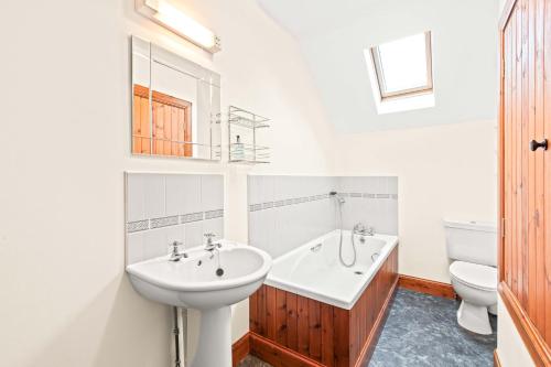 La salle de bains blanche est pourvue d'un lavabo et de toilettes. dans l'établissement Freuchies Mill - A Holiday Home For All Seasons., à Blairgowrie