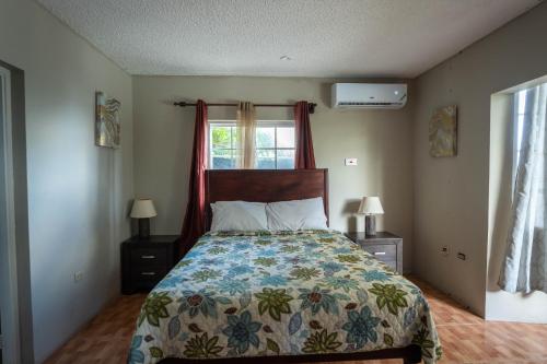 1 dormitorio con 1 cama con colcha de flores y ventana en Chrisann's Beach Resort, en Saint Mary
