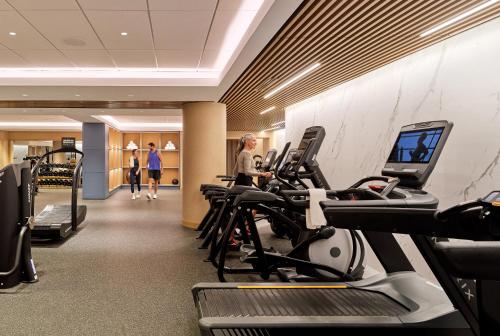 a gym with cardio equipment and people walking in the background at The Charles Hotel in Harvard Square in Cambridge
