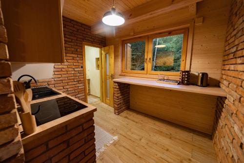 a kitchen in a log cabin with a sink and a window at Chata Domaša - Nová Kelča in Valkov