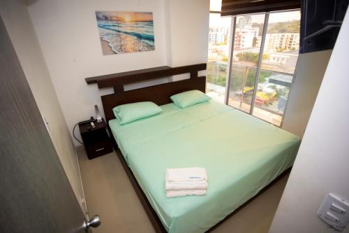 a small bedroom with a green bed with a window at Hermoso departamento frente al mar, Arena Plaza in Tonsupa