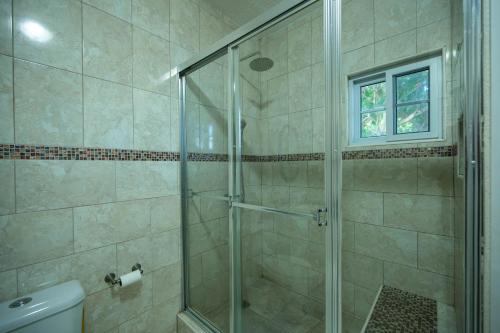 y baño con ducha y puerta de cristal. en Chrisann's Beach Resort, en Saint Mary