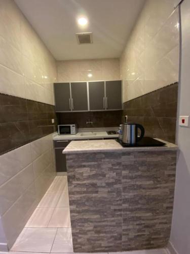 a kitchen with a counter with a stove and a microwave at بيوتات المروة للشقق المخدومة biutat almarwa in Jeddah