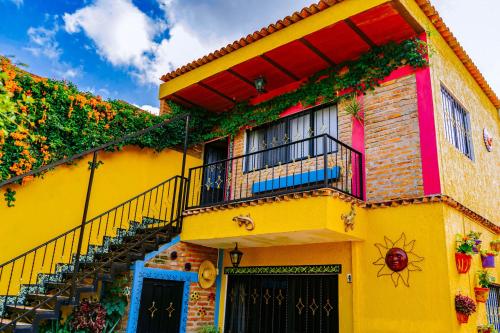 um edifício amarelo com varanda e escadas em Posada las Margaritas em Guadalajara