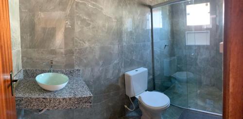 La salle de bains est pourvue de toilettes et d'une douche en verre. dans l'établissement Pousada Licuri Ibicoara, à Ibicoara