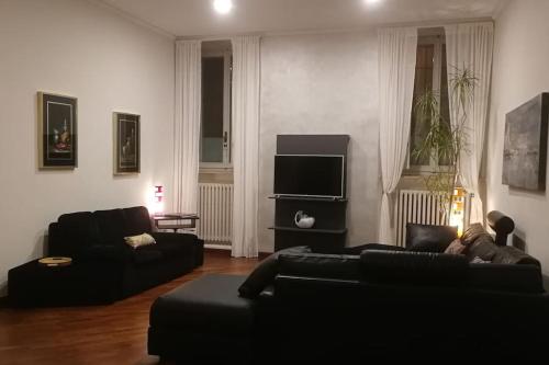 ein Wohnzimmer mit einem schwarzen Sofa und einem TV in der Unterkunft Appartamento Crisopoli in pieno centro a Parma in Parma