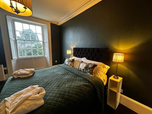 a bedroom with a bed with a green comforter and a window at Penthouse apartment in Cockermouth