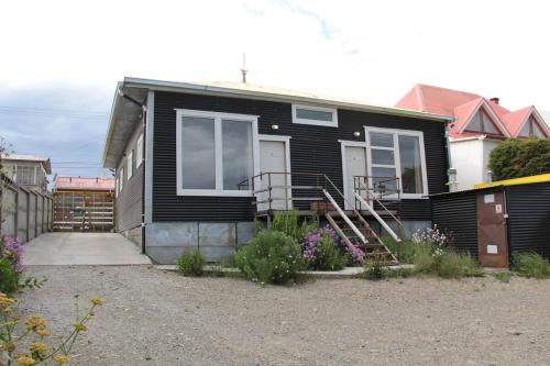 Una casa negra con porche y escaleras. en Hostal El Mesón, en Punta Arenas
