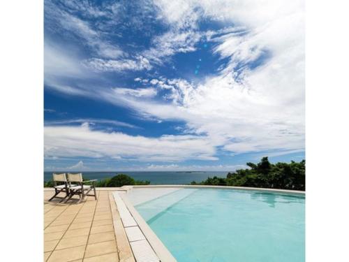 a swimming pool with two chairs and the ocean at Hotel Hamahigashima Resort - Vacation STAY 10570v in Uruma