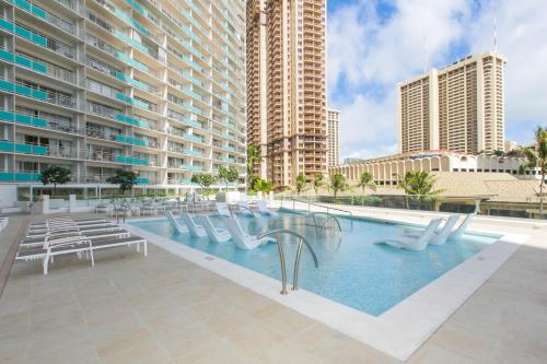 uma piscina com cadeiras brancas e edifícios altos em Ilikai Tower 1533 Yacht Harbor View 1BR em Honolulu