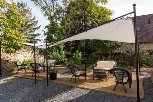 a patio with chairs and a white umbrella at ESTER'S Szentbékkálla in Szentbékkálla