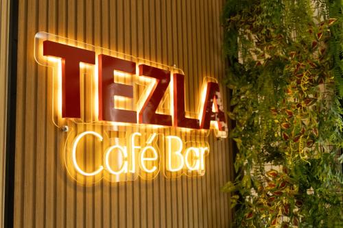 a neon coffee bar sign on the side of a building at Tezla Hotel in Primavera do Leste