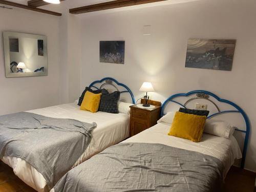 two twin beds in a room with two lamps at Apartamentos Ines in Valdelinares