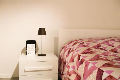 a bedroom with a bed and a lamp on a dresser at HEATHER'S HOME 110 Apt 400mt from Old Bridge in Bassano del Grappa