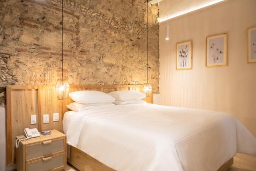 um quarto com uma cama branca e uma parede de pedra em Hotel Casa La Mantilla by Faranda Boutique em Cartagena das Índias