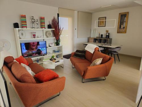 a living room with two chairs and a flat screen tv at The Panoramic Penthouse in Orihuela